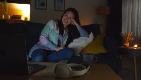 Smiling-Woman-Sitting-On-Sofa-At-Home-At-Night-Streaming-Or-Watching-Movie-Or-Show-On-Laptop-7